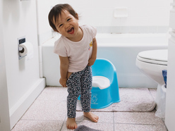toddler girl smiling in bathroom while potty training
