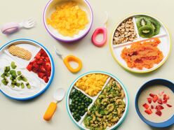 A tablescape with various colored baby foods and purees on plates