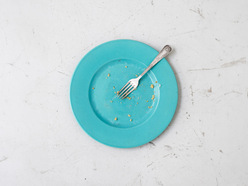 an empty blue dinner plate with a fork on it